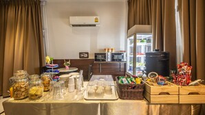 A hotel room with a buffet setup, including jars of snacks, a microwave, and a refrigerator. - At 42 Residence (Bangkok)
