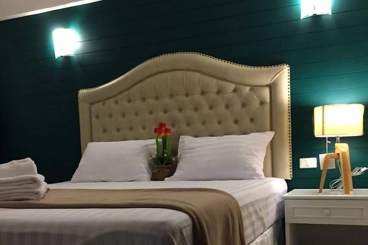 A bed with a tufted headboard, white pillows, and a beige bedspread.