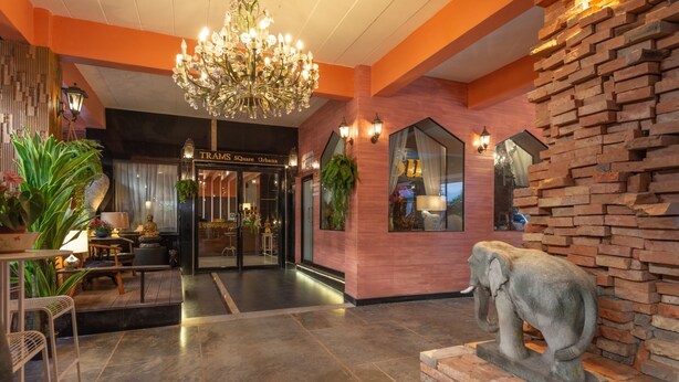 A lobby with a chandelier, brick wall, and a statue of an elephant. - At 42 Residence (Bangkok)