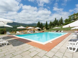 Relax by the pool surrounded by lush greenery and distant mountains.
