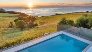 Una piscina con vista al océano al atardecer.