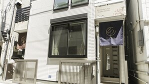 Ein Hotel Eingang mit einem großen Fenster, einem Metallgitter und einem Schuhregal vor der Tür.