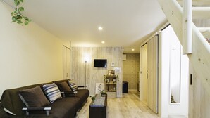 Ein modernes Wohnzimmer mit einer Couch, einem Couchtisch und einem an der Wand befestigten Fernseher.
