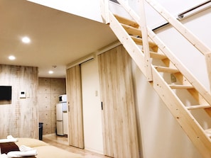 Moderni hotellihuone, jossa on puinen portaikko, suuri liukuovi ja pieni keittotila.