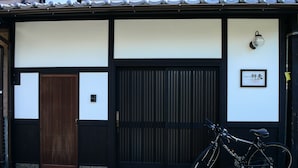 Een traditioneel Japans gebouw met een houten deur, een zwarte schuifdeur, en een fiets voor de ingang.