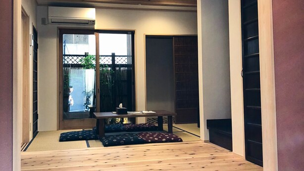 Een traditioneel Japans interieur met tatami vloeren, een lage tafel met kussens en een schuifdeur.
