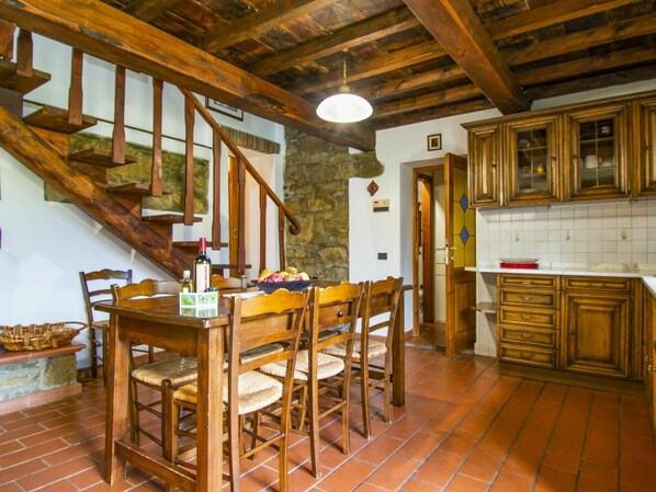 A rustic kitchen with wooden furniture, a stone wall, and a tiled floor.