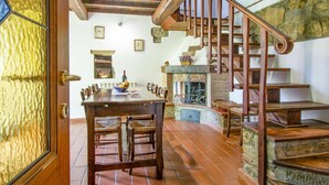 A rustic interior with a wooden staircase, a dining area with a table and chairs, and a stone fireplace. - Beautiful apartment in villa for 6 people with WIFI, pool and terrace (Malva Nuova Squarcia)
