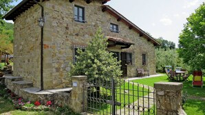 A stone house with a small porch, a metal gate, and a garden with flowers. - Beautiful apartment in villa for 6 people with WIFI, pool and terrace (Malva Nuova Squarcia)