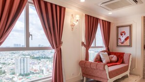 A room with a large window, a red sofa, and a framed picture on the wall.