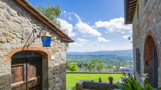 A stone building with a wooden door and a view of a green landscape. - Lovely apartment in villa for 4 people with pool, WIFI (Loro Ciuffenna)