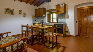 A rustic kitchen with wooden cabinets, a dining table with chairs, and a hanging light fixture. - Lovely apartment in villa for 4 people with pool, WIFI (Loro Ciuffenna)