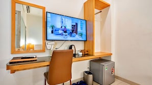 A modern hotel room with a flat-screen TV mounted on the wall, a wooden desk with a chair, a small refrigerator, and a trash bin. - S79 Son Mi Hotel 839 Le Hong Phong Street (Ho Chi Minh City)