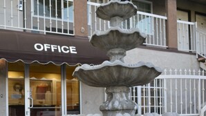 A multi-tiered stone fountain with terracotta pots on either side, in front of a building with a sign that reads "OFFICE". - Bell Gardens Inn Los Angeles - Bell Gardens (Bell Gardens)