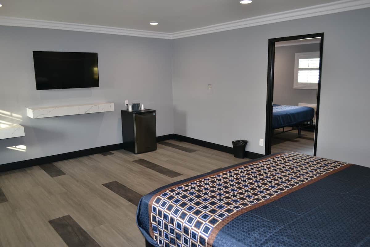 A hotel room with a bed, a TV mounted on the wall, a small desk, and a mirror.