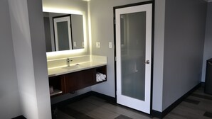 A modern bathroom with a vanity, mirror, and frosted glass door. - Bell Gardens Inn Los Angeles - Bell Gardens (Bell Gardens)