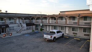A motel with a white pickup truck parked in the parking lot, multiple balconies, and a visible office building. - Bell Gardens Inn Los Angeles - Bell Gardens (Bell Gardens)