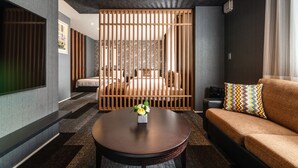 Quarto de hotel moderno com uma cama grande, um sofá, uma televisão e um divisória de madeira.