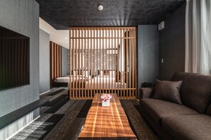 Uma sala de estar moderna com um sofá, uma mesa de centro de madeira com um arranjo floral e um painel deslizante.