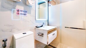 Une salle de bain moderne avec un mur en marbre, un lavabo avec un miroir, des toilettes et un espace douche.