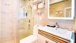 Een moderne badkamer met een douchecabine van glas, een wit wastafelmeubel met gouden accenten en een spiegel met verlichte lijst.