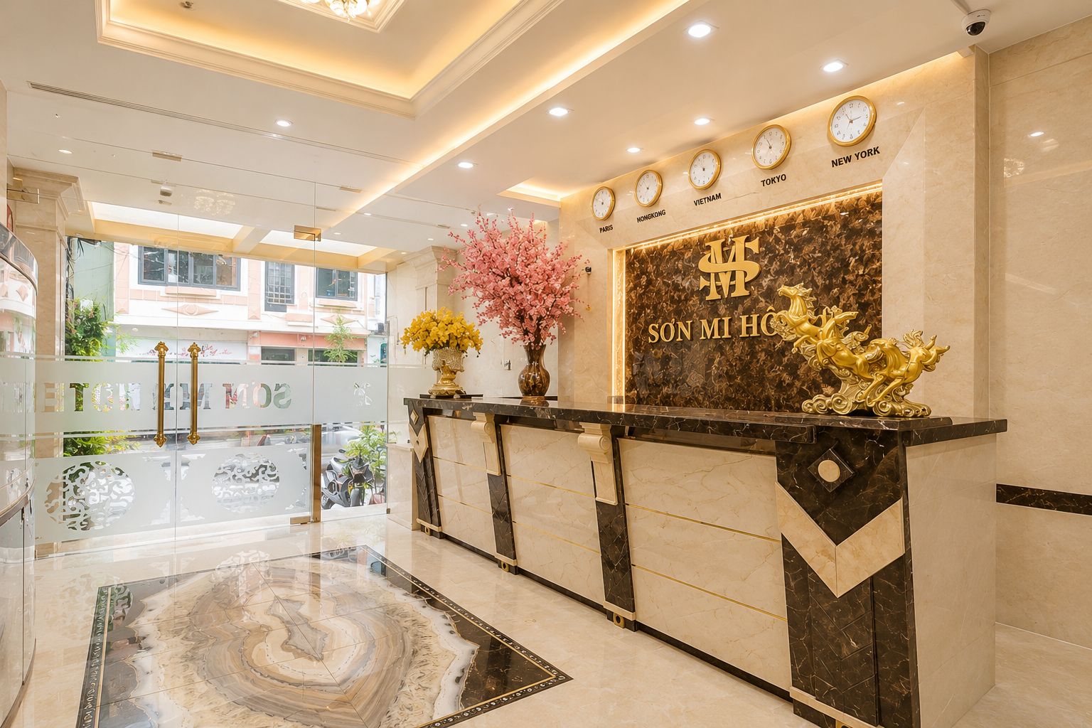 A hotel reception desk with a marble floor, a clock displaying multiple time zones, and a decorative golden horse sculpture.