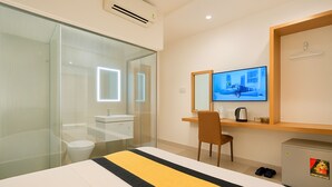Une chambre d’hôtel comprenant un lit, un bureau, une chaise, une télévision, un miroir, une armoire et un petit meuble de rangement.