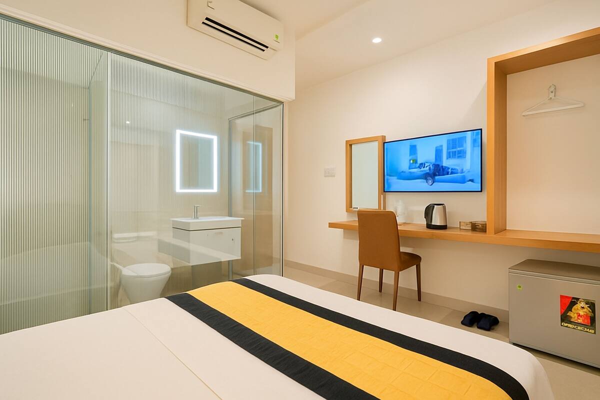 Una habitación de hotel con cama, escritorio, silla, televisión y minibar.