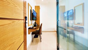 Een moderne hotelkamer met een houten garderobe, een bureau met stoel, een flatscreen televisie en een groot raam met uitzicht.