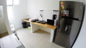 Een kleine keuken met een roestvrijstalen koelkast, een magnetron en een houten aanrecht.