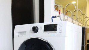 Een voorlader wasmachine, wit, met een digitaal bedieningspaneel en een deur van roestvrij staal.