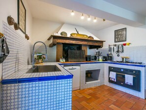 A kitchen with a blue and white tiled backsplash, a wooden countertop, a built-in oven, and a hanging rack with utensils. - Cosy apartment in villa for 10 guests with private pool, WIFI, TV, terrace and pets allowed (Greve In Chianti)