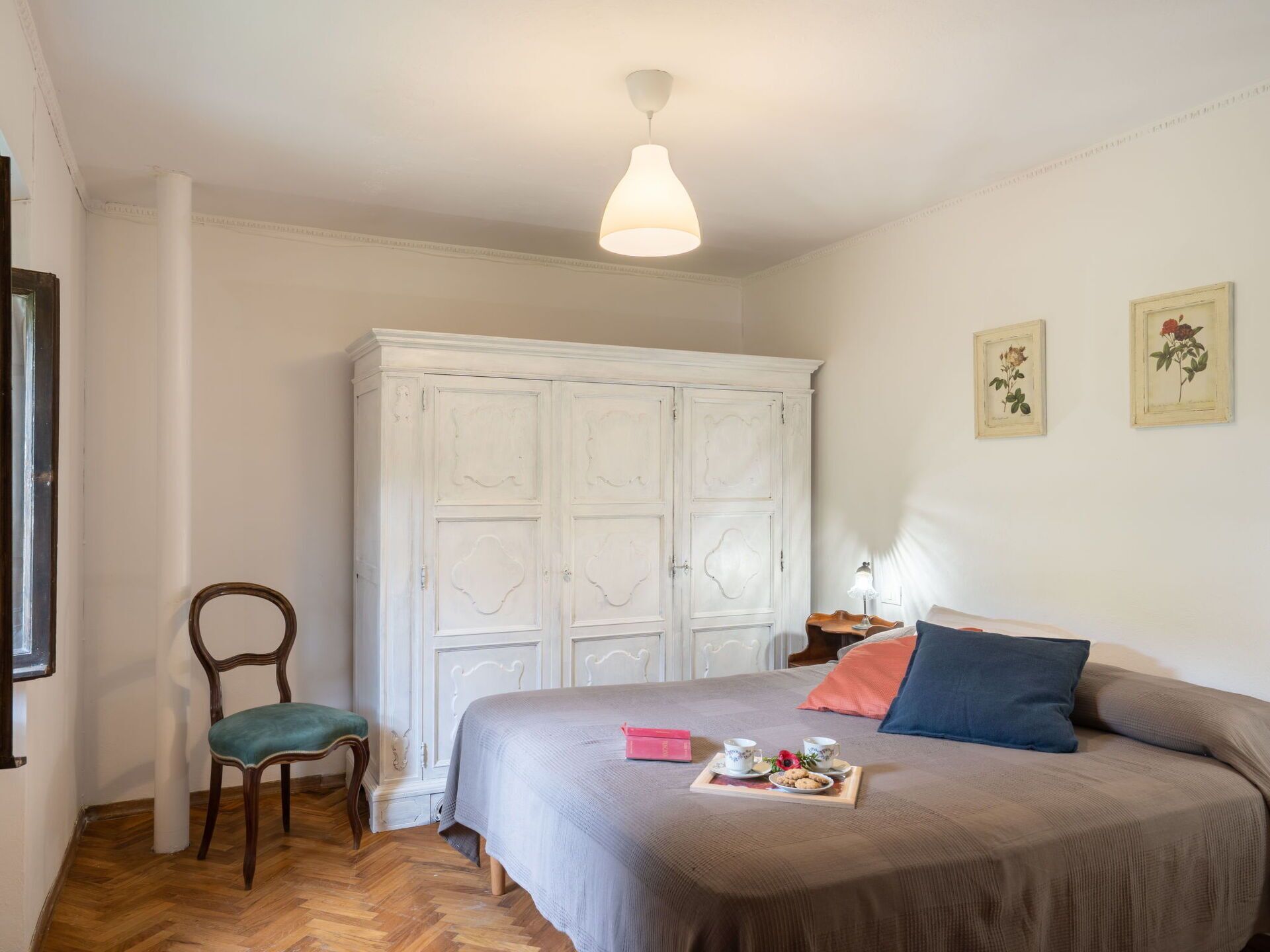 Een slaapkamer met een bed, een kledingkast, een stoel en een kleine tafel met een dienblad.