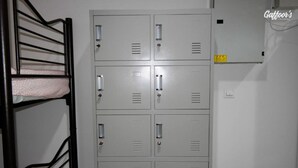 A bunk bed with a pink and white patterned mattress, a metal bunk ladder, and a grey metal locker room with multiple lockers. - Resort Hostel In City (Kuala Lumpur)