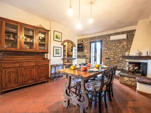 Un espace repas comprenant une table en bois, des chaises et un mur en pierre.