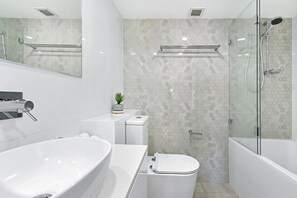 A modern bathroom with a freestanding bathtub, a toilet, and a glass-enclosed shower area.