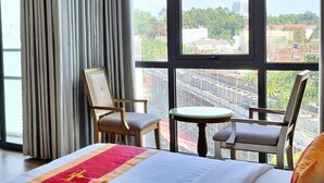 A hotel room with a bed, a desk with a refrigerator, a chair, a small table, and a TV. - S79 Anh Duc Hotel 2 (Ho Chi Minh City)