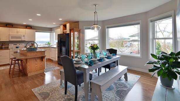 Een moderne keuken met een centraal eiland, houten kastjes en een eetgedeelte met een bank en stoelen.