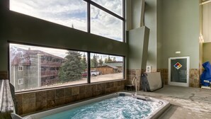 Ein großes Innen-Whirlpool mit Blick auf eine Wohngegend durch große Fenster.