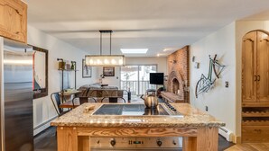 Eine moderne Küche mit Granit Arbeitsplatte, Edelstahlgeräten und einem Essbereich mit Sofa und Tisch.