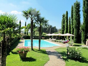 A swimming pool surrounded by palm trees and a lawn with lounge chairs and umbrellas. - Cosy apartment in villa for 4 guests with WIFI, pool, TV, terrace and pets allowed (Poggibonsi)