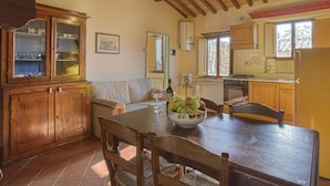A rustic kitchen with wooden cabinets, a dining table, and a cozy seating area. - Nice apartment for 4 people with WIFI, pool, TV, patio, pets allowed and panoramic view (Tavarnelle Val Di Pesa)