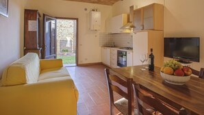 Un angolo cottura compatto con tavolo da pranzo, divano e televisore.