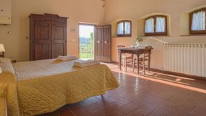 Una camera da letto con un letto, un armadio in legno, un tavolo con sedie e vista sull'esterno.
