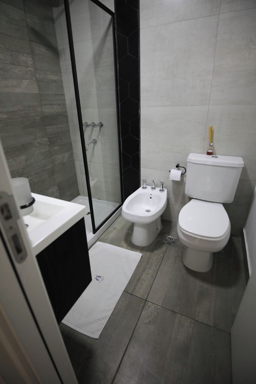 Un baño moderno con cabina de ducha de vidrio, un bidé, un inodoro y un lavabo.