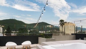 A rooftop terrace with a hot tub, two white cushioned seating areas, and string lights. - Anden by FMA Coliving (Salta)