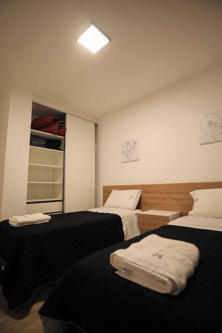 A hotel room with two beds, a wardrobe, and artwork on the walls.