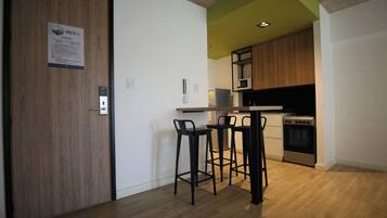 Une cuisine moderne avec des meubles en bois, un four à micro-ondes et une cuisinière. On y trouve trois tabourets de bar noirs et un comptoir blanc.