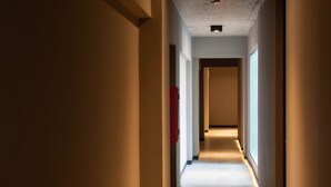 A narrow, well-lit hallway with a tiled floor and a ceiling with recessed lighting. - Anden by FMA Coliving (Salta)