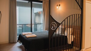 A modern hotel room with a large bed, a balcony, and a staircase with a unique design. - Anden by FMA Coliving (Salta)